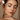 A woman with closed eyes applies serum to her freckled face for skincare, enhancing natural beauty.